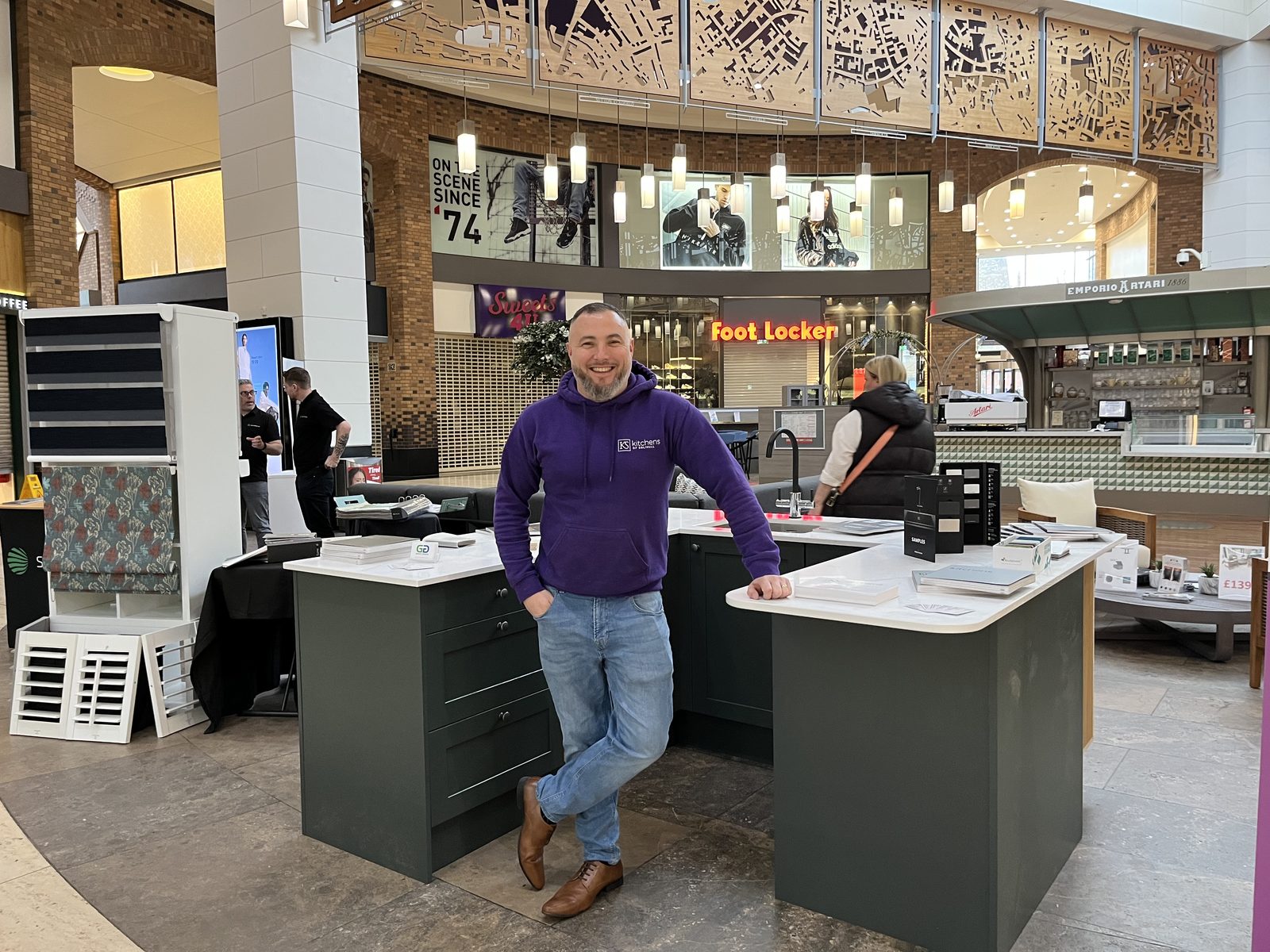 Steve Harris at a Kitchens of Solihull display, showing the grey shaker and handleless finishes clients can see and handle before they decide.